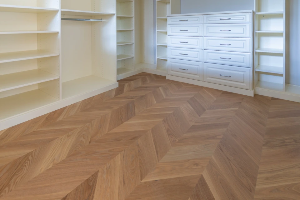 White oak chevron floor in a walk-in closet with built-in storage
