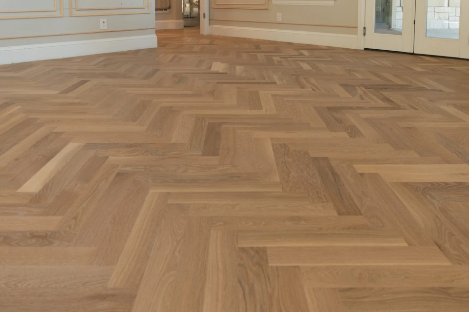 Low-angle view across the white oak herringbone pattern