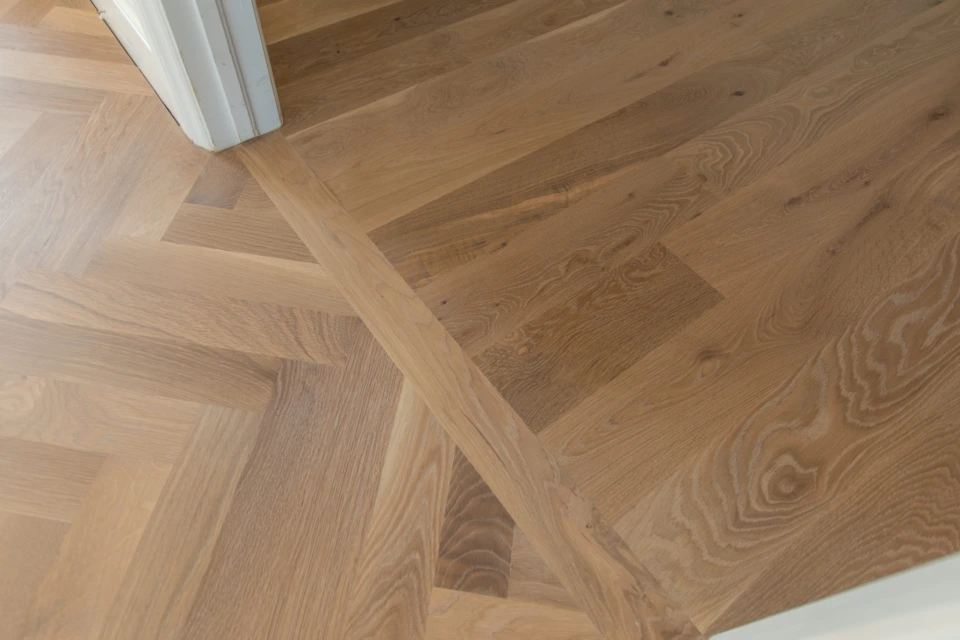 Bordered transition between herringbone and straight-plank white oak flooring