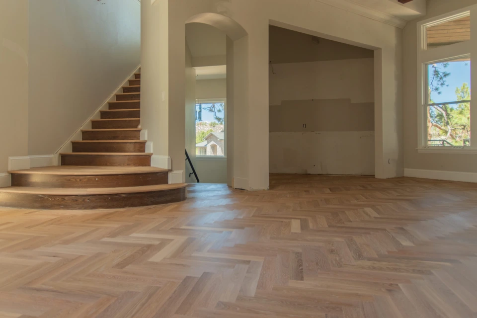 Refinished wood staircase beside a white oak herringbone floor