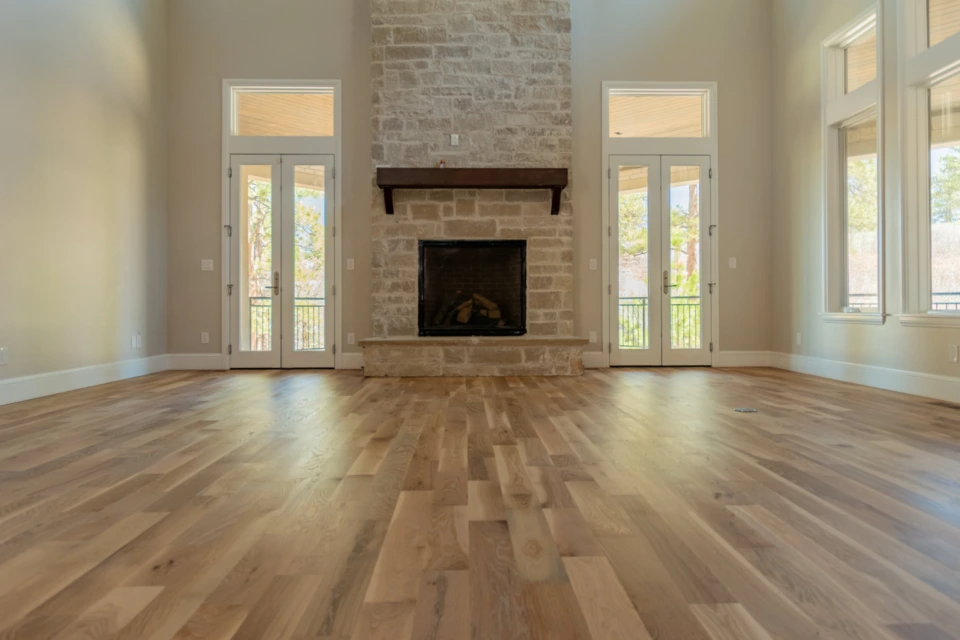 Straight-plank white oak floor extending toward a centered stone fireplace